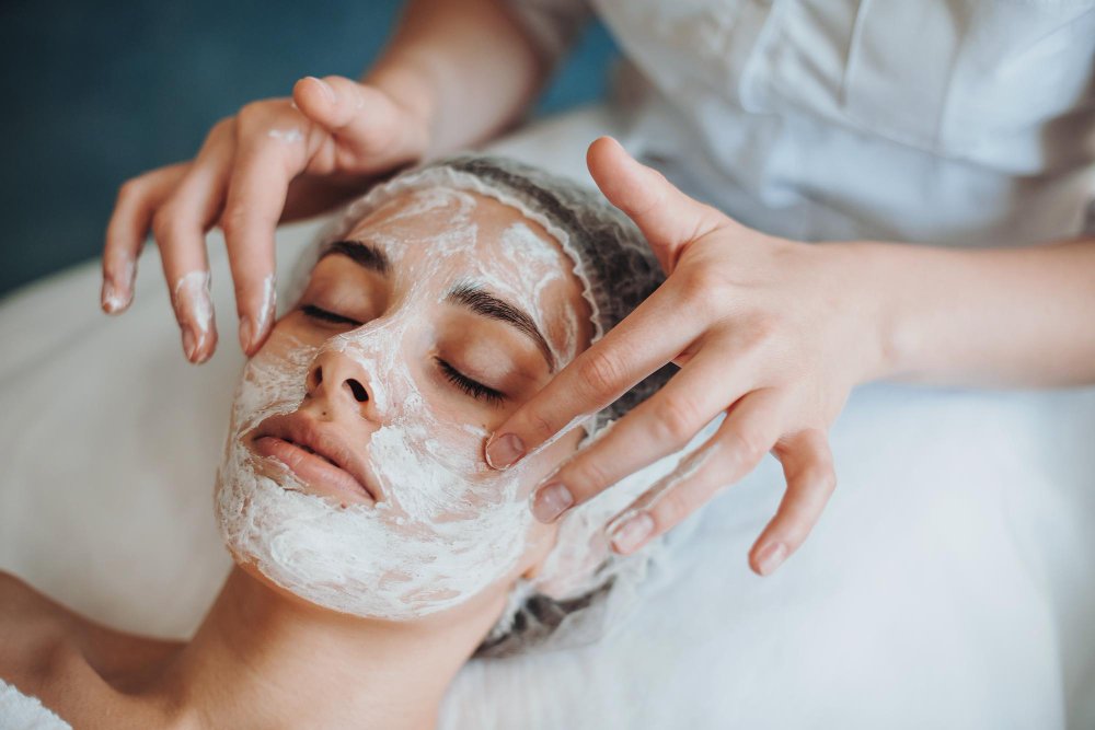 primer plano retrato de manos de cosmetólogos aplicando máscara en la cara del cliente en salón de spa belleza natural f ...