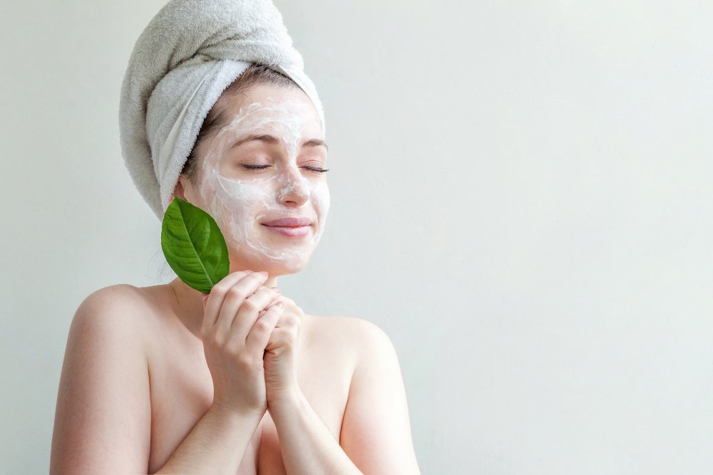 retrato de mujer con toalla en la cabeza aplicando peeling de enzimas en la cara