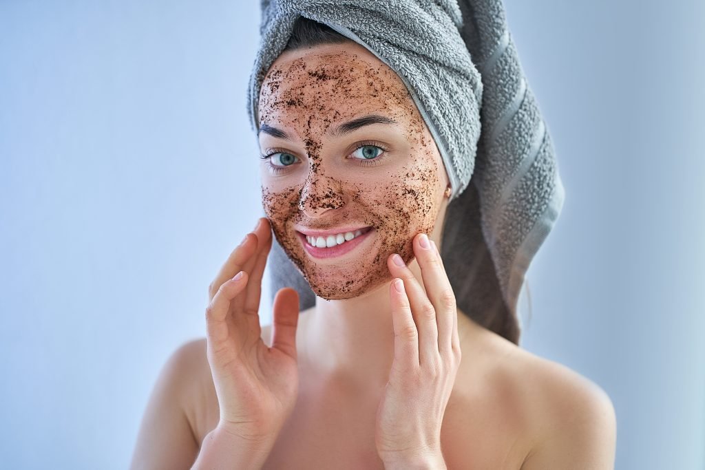 mujer feliz, sana y sonriente en una toalla de baño con un exfoliante de café facial natural