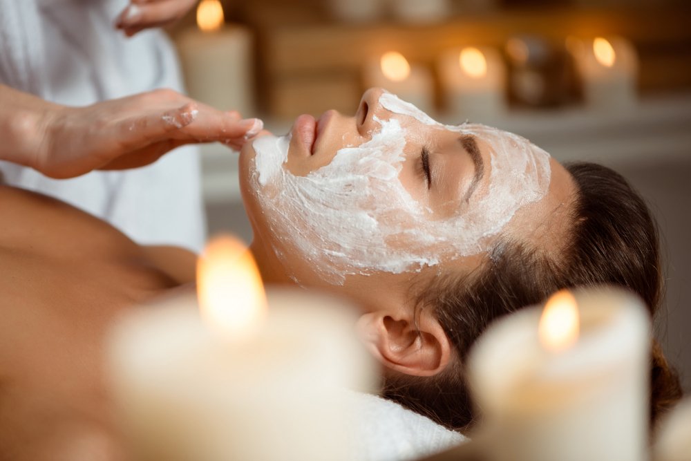 mujer joven con máscarilla exfoliante en salón de belleza